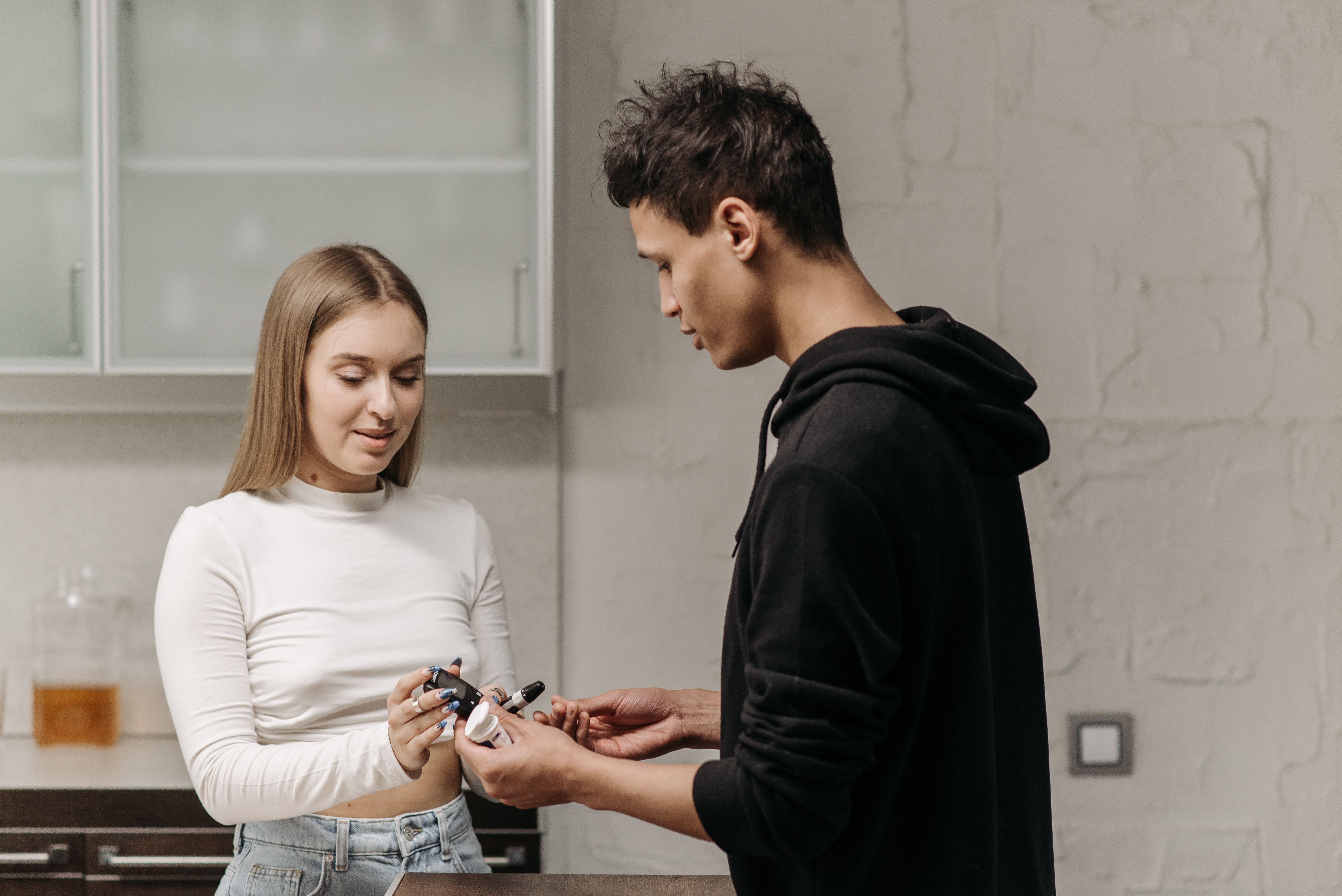 A woman handing a glucose meter to a man for blood sugar monitoring